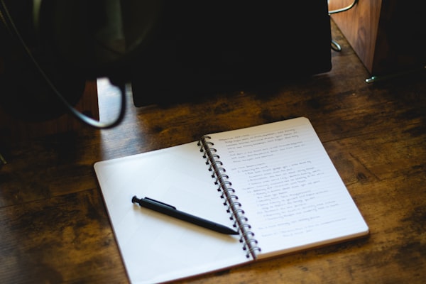 An open notebook with a pen on a wooden desk