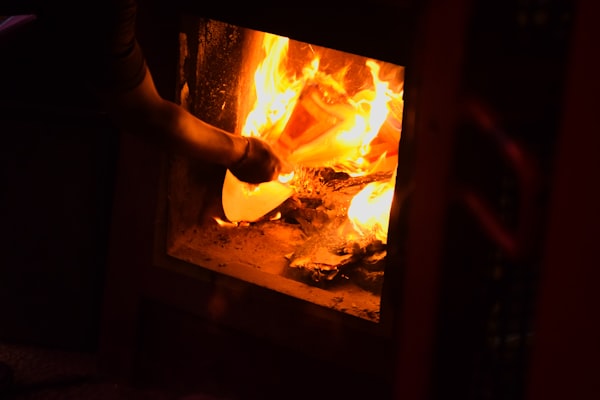 A person places a pizza into a wood-fired oven.