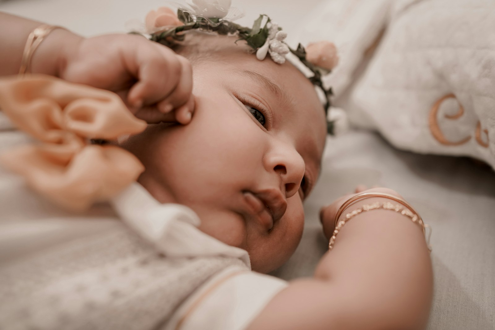 A little girl laying on a bed with a flower in her hair