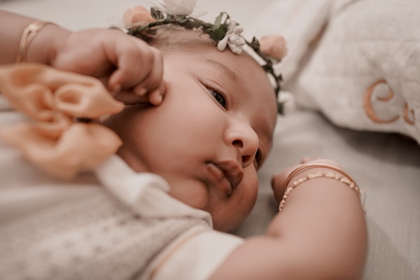 A little girl laying on a bed with a flower in her hair